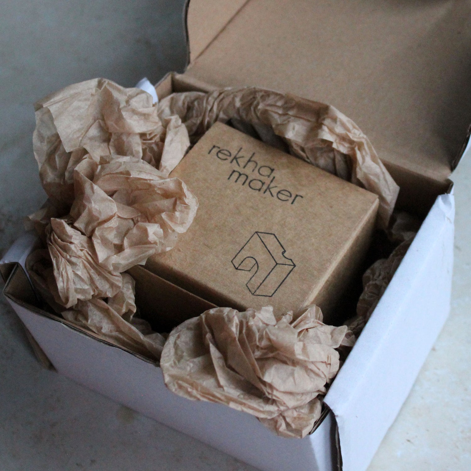 Unwrapping a Rekha Maker candleholder in her sustainable packaging.